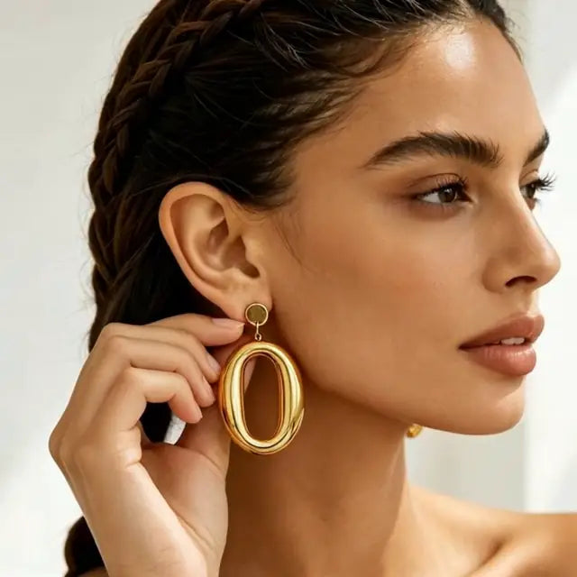 Aurora Drops gold oval earrings worn by a model